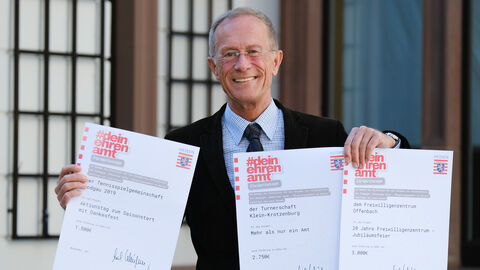 Staatsminister Axel Wintermeyer hält mehrere Förderungsbescheide in die Kamera