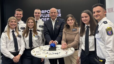 Innenminister Poseck steht mit sechs Polizistinnen und Polizisten in Ausbildung um einen Stehtisch herum.